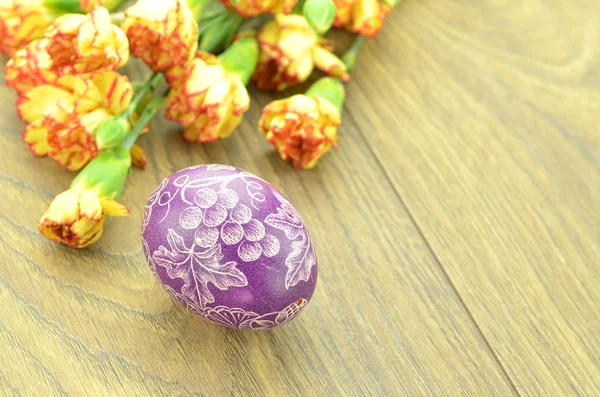 Scratched handmade Easter egg and carnation flowers — Stock Photo, Image