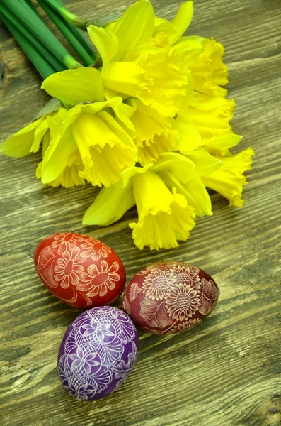 Hermosos huevos de Pascua hechos a mano arañados y flores de narciso — Foto de Stock