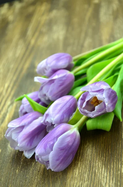 Kytice krásné fialové tulipány na rustikální dřevěný stůl — Stock fotografie