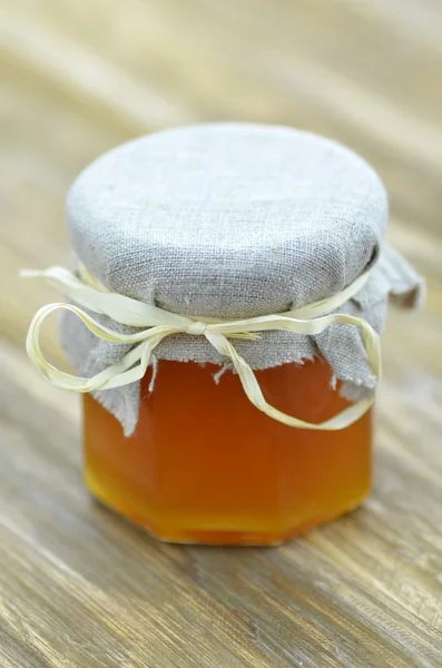 Tarro de miel fresca y deliciosa en una mesa de madera — Foto de Stock