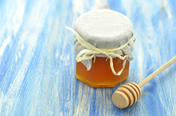 Jar of fresh delicious honey and honey dipper on a wooden table — Stock Photo, Image