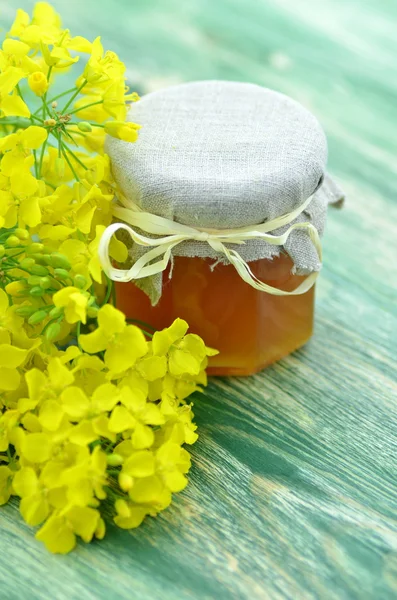 Barattolo di delizioso miele in un barattolo con fiori di colza — Foto Stock