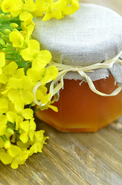 Tarro de deliciosa miel en un frasco con flores de colza — Foto de Stock