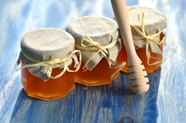 Tuffatore di miele in legno e vasetti pieni di delizioso miele fresco in apiario — Foto Stock