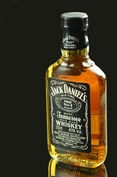 Pequena garrafa de uísque Jack Daniels isolado no fundo escuro — Fotografia de Stock