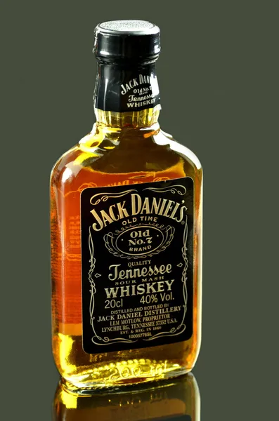 Piccola bottiglia di whisky Jack Daniels isolata su sfondo scuro — Foto Stock