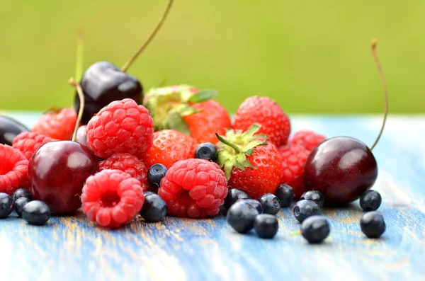 Variety of soft fruits, strawberries, raspberries, cherries, blueberries on table in the garden — Stock Photo, Image