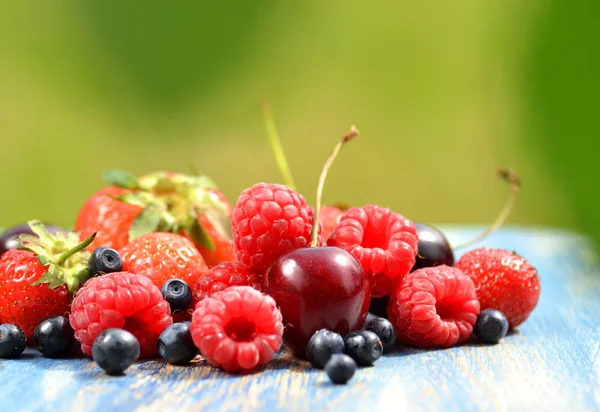 Variety of soft fruits, strawberries, raspberries, cherries, blueberries on table in the garden — Stock Photo, Image