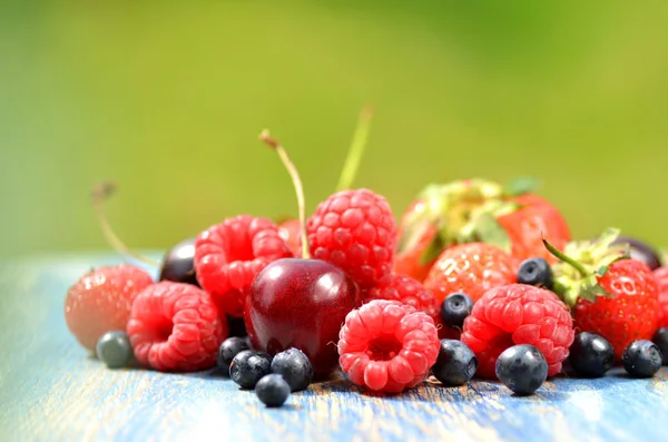 Variedad de frutas suaves, fresas, frambuesas, cerezas, arándanos en la mesa en el jardín —  Fotos de Stock