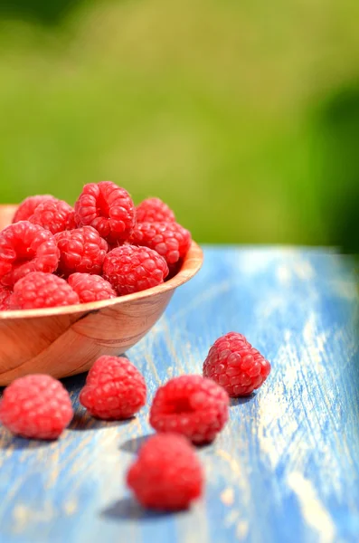 Primer plano de frambuesas maduras, frescas y dulces en un tazón sobre la mesa en el jardín —  Fotos de Stock