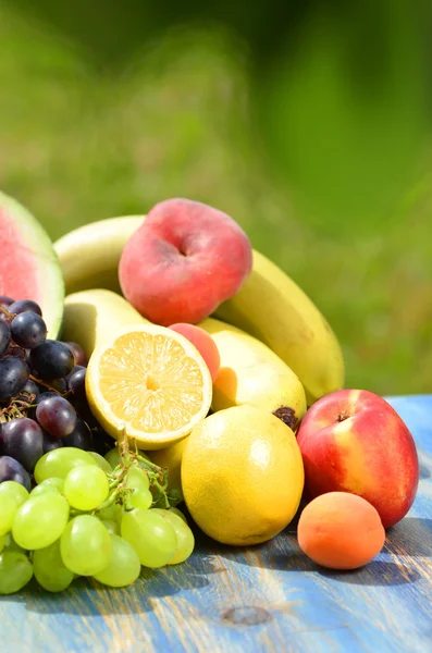 Разнообразие фруктов на столе в саду — стоковое фото