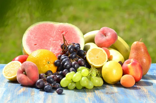 Разнообразие фруктов на столе в саду — стоковое фото