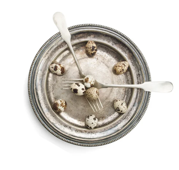 Clock made of quail eggs on silver plate with forks — Stock Photo, Image
