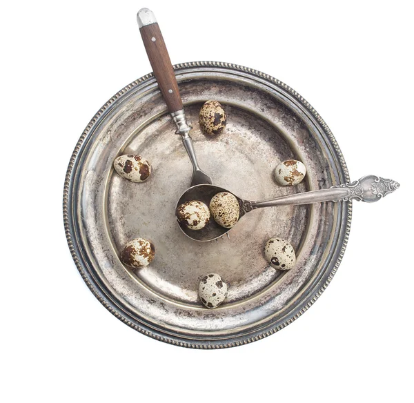Clock made of quail eggs on silver plate with fork and spoon, isolated on white background — Stock Photo, Image