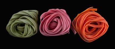 Fettuccine makarna renkli iç içe. siyah arka plan üzerine izole