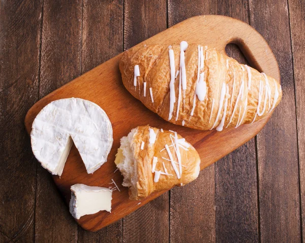 Croissant och ost på träskiva — Stockfoto