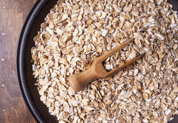 Plate with raw oatmeal on wooden table. — Stock Photo, Image