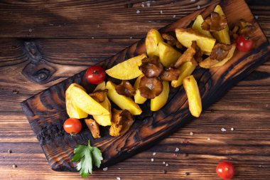 Masadaki tahtanın üzerinde kızarmış patates ve chanterelles..