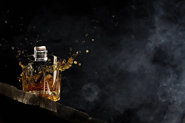 Viski bardakta, siyah bir arka planda, tahta bir masada. — Stok fotoğraf