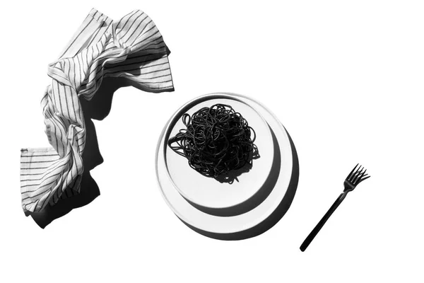 Macarrão preto em uma placa branca em um fundo branco. conceito não é pratos comuns. Depósito plano. — Fotografia de Stock