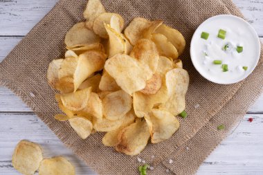 Beyaz ahşap arka planda lezzetli altın patates cipsi.