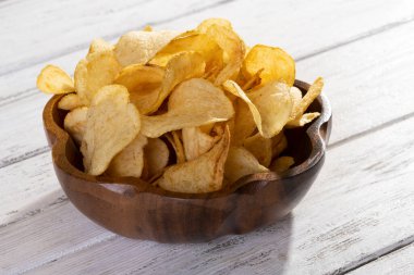 Beyaz ahşap arka planda lezzetli altın patates cipsi.