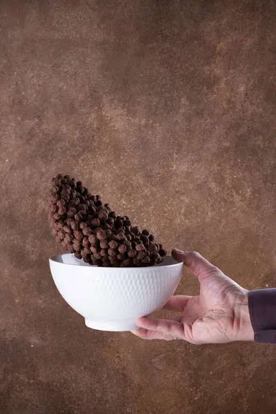Падение шоколадных шариков в белую миску на коричневом фоне. levitation. — стоковое фото