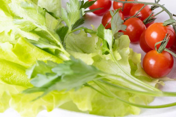 Beyaz arka planda beyaz bir tabakta domates ve maydanoz..