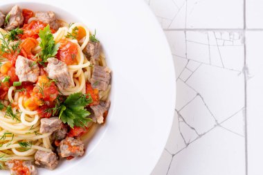Domates soslu makarna, beyaz tabakta et ve beyaz seramik arka plan. Üst görünüm