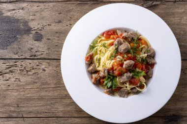 domates soslu makarna ve beyaz tabakta et ve ahşap zemin.