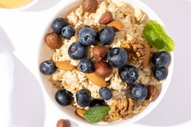 Beyaz masa manzaralı yulaf lapası, yaban mersini ve fındık. Sağlıklı kahvaltı ve diyet yemek..