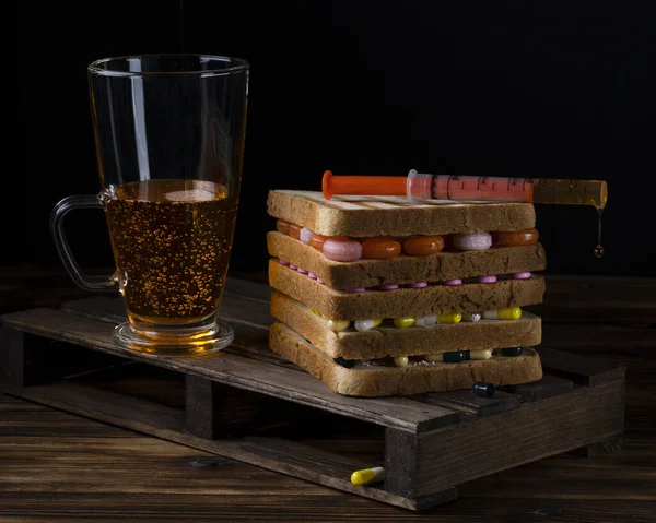 濃い色の背景に錠剤と混合物のガラスでサンドイッチ — ストック写真
