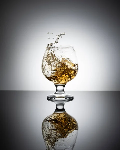 Splash Cognac Glas Geïsoleerd Een Lichte Achtergrond — Stockfoto