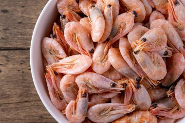 Tahta arka planda beyaz bir tabakta karides..