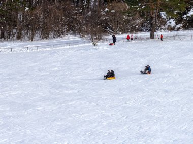 Maykop, Adygea Cumhuriyeti, Rusya Federasyonu, 01. - 24. 2021: Dağlarda aile tatili, dondurucu kış sabahı, kar motosikleti ve şişme kızak, yeni yıl tatili.