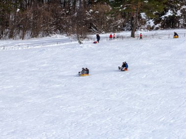Maykop, Adygea Cumhuriyeti, Rusya Federasyonu, 01. - 24. 2021: Dağlarda aile tatili, dondurucu kış sabahı, kar motosikleti ve şişme kızak, yeni yıl tatili.
