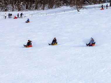 Maykop, Adygea Cumhuriyeti, Rusya Federasyonu, 01. - 24. 2021: Dağlarda aile tatili, dondurucu kış sabahı, kar motosikleti ve şişme kızak, yeni yıl tatili.
