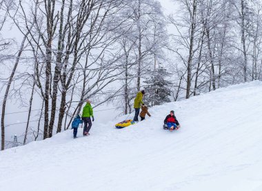 Maykop, Adygea Bölgesi, Rusya Federasyonu, 01.30.2022: Dağlarda aile tatili, soğuk kış sabahı, kaykay, kayak, şişme kızak, cheesecake .