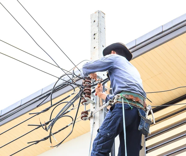 Elettricista collega fili su un palo — Foto Stock