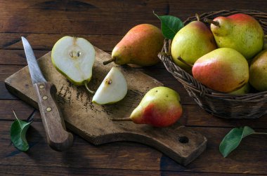 Sepette olgun armutlar ve ahşap mutfak tahtasının üzerinde antika bir bıçak. Kırsal biçim.