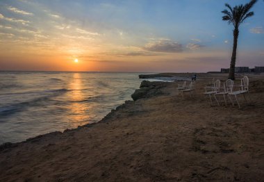 Denizde güzel bir gün doğumu. Kızıl Deniz 'de şafak vakti. Güneş, denize yansıyor. Mavi şafak gökyüzünde hafif bulutlar. Deniz kenarındaki güzel sandalyeler. Tropik gün doğumu
