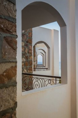 EGYPT. LUXOR - 10.10.2021. Beyaz binanın koridor ve kemerleri güneş ve deniz manzarasıyla aydınlatılır. Mimari simetri. Kısaltmalar Arap tarzında birer birer kemerler.