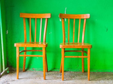 Beton yeşil bir duvarın arka planında eski ahşap tabureler. Merdivenlerdeki eski mobilyalar.