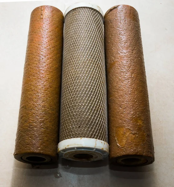 Dirty used reverse osmosis system cartridges on a kitchen background. Elements of a filtration system for clean and healthy water.
