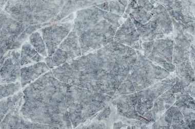 Çatlamış buz ve sarı yapraklar. Sarı yapraklar ve beton çatlamış buzun altında görülebilir.