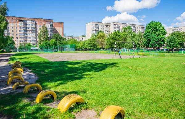 Eski futbol sahası ve paslı beyaz futbol topu okulun yakınındaki şehirde. Çimlerle kaplı eski futbol sahası. Çocuklar için eski beton futbol sahası. Okulun yakınındaki eski stadyum.