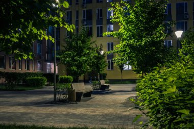 Night park paths and colored houses at summer night. Night paths, benches and lanterns in a beautiful residential complex. Night summer park with lanterns and benches. Kyiv. Ukraine
