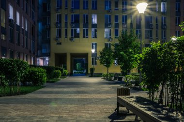 Night park paths and colored houses at summer night. Night paths, benches and lanterns in a beautiful residential complex. Night summer park with lanterns and benches. Kyiv. Ukraine
