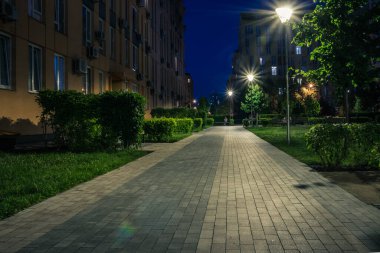 Night park paths and colored houses at summer night. Night paths, benches and lanterns in a beautiful residential complex. Night summer park with lanterns and benches. Kyiv. Ukraine