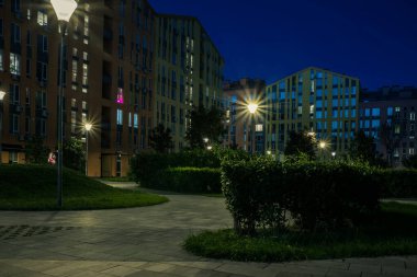 Night park paths and colored houses at summer night. Night paths, benches and lanterns in a beautiful residential complex. Night summer park with lanterns and benches. Kyiv. Ukraine
